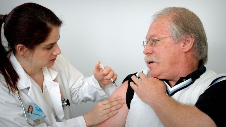 middle-aged-man-receiving-an-intramuscular-immunization-into-his-left-shoulder-muscle-from-a-female-nurse-725x479